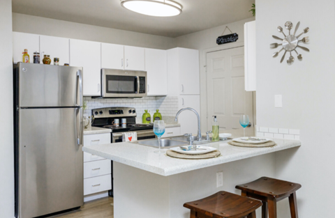 A kitchen with a refrigerator, microwave, and stove top oven.