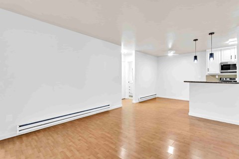 A spacious room with wooden flooring and white walls.