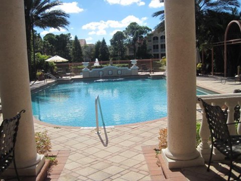 A pool with a diving board is surrounded by columns.