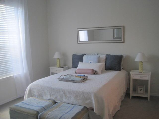 A bedroom with a bed, two lamps, and a mirror.