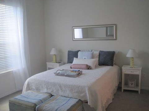 A bedroom with a bed, two lamps, and a mirror.