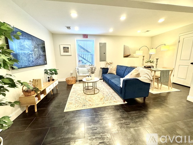 A living room with a blue couch and a rug.