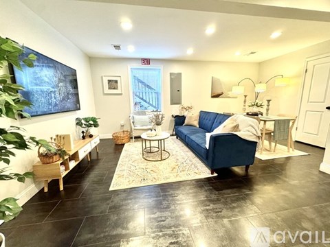 A living room with a blue couch and a rug.