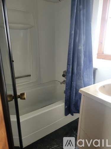 A bathroom with a white tub and blue shower curtain.