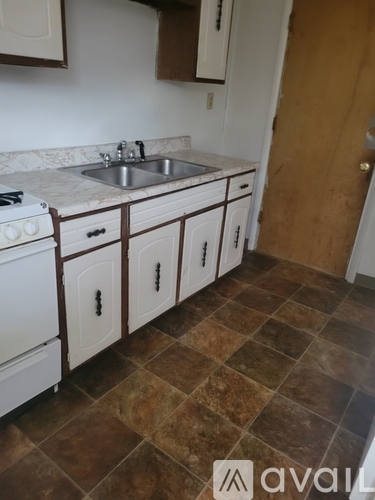 A kitchen with a white stove top oven and white cabinets.