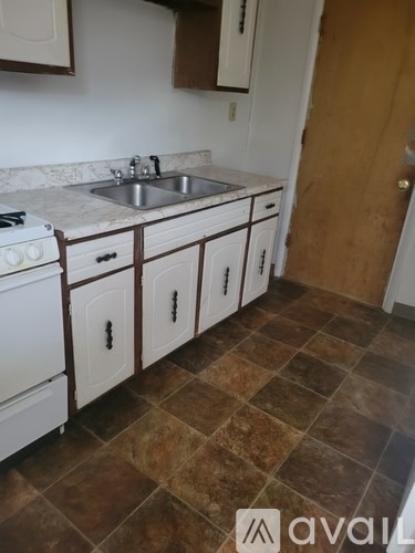 A kitchen with a white stove top oven and white cabinets.