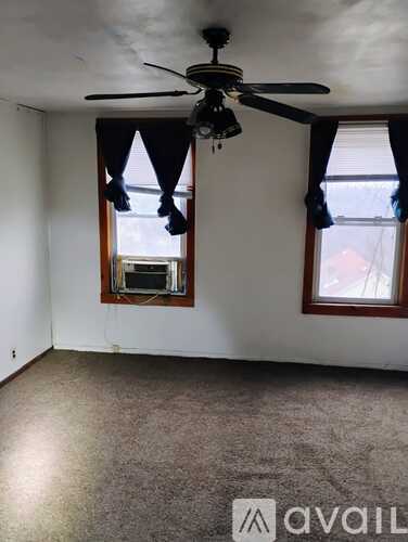 A room with a ceiling fan and two windows.