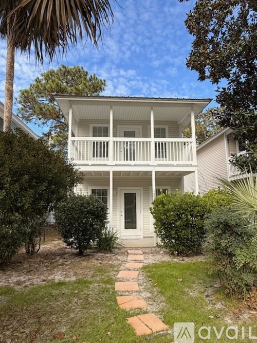 A white house with a balcony and a small garden in front.