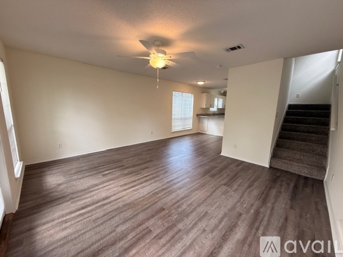A spacious room with wooden flooring and a staircase leading to another level.
