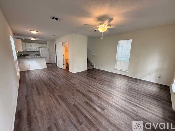 A spacious room with wooden flooring and a ceiling fan.