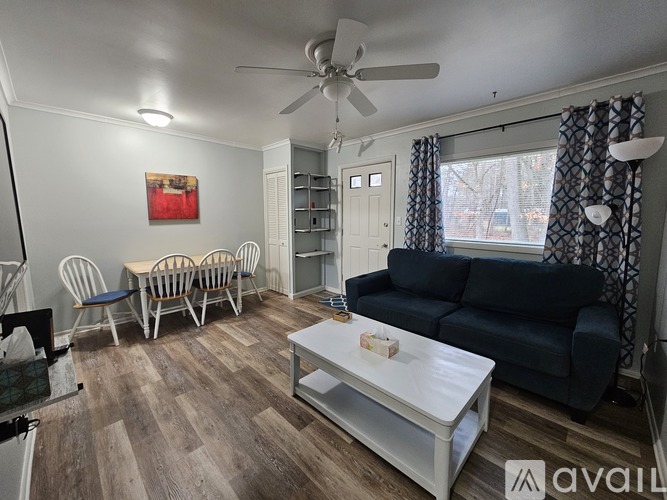A living room with a black couch, a white coffee table, and a ceiling fan.