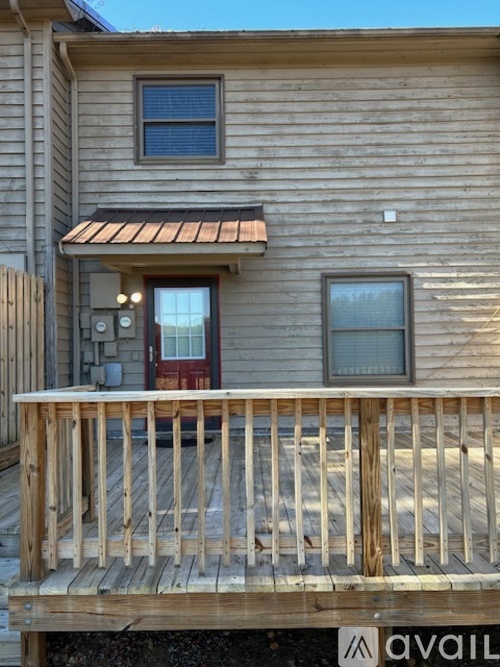 A wooden house with a red door and a balcony.