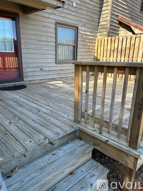 A wooden deck with a red door and window.