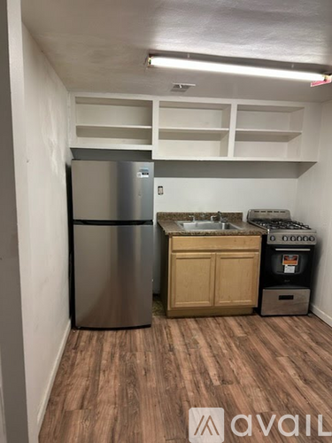 A kitchen area with a refrigerator, sink, and cabinets.
