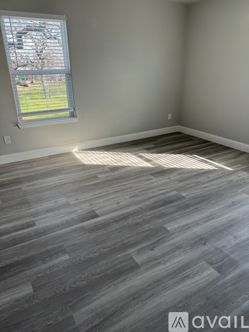 A room with a large window and wooden flooring.