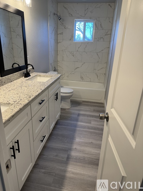 A bathroom with a marble tile shower and a white toilet.