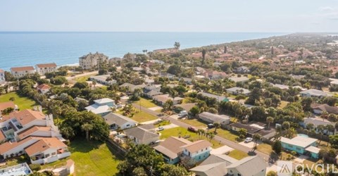 A bird's eye view of a coastal residential area with houses and greenery.