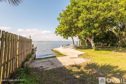 A wooden fence borders a grassy area next to a body of water.