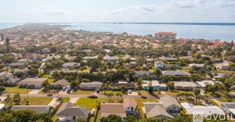 A bird's eye view of a residential area with houses and a body of water in the distance.