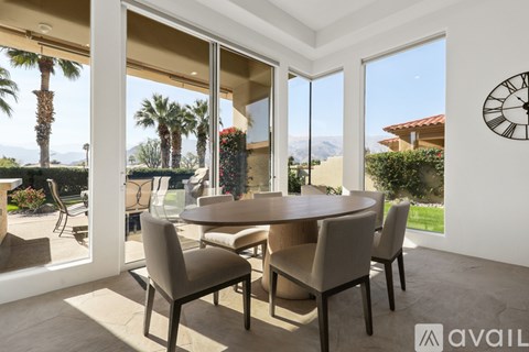 A dining room with a table and chairs and a view of the outdoors through the sliding glass doors.