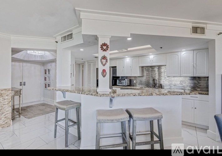 A kitchen with white cabinets and a marble countertop.