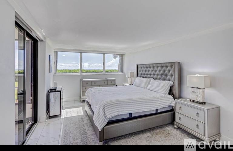 A bedroom with a large bed, nightstand, and window.