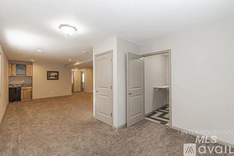 A spacious room with a carpeted floor and a doorway leading to another room.