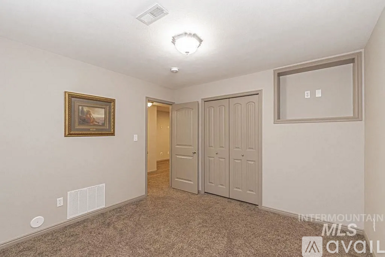 A bedroom with a brown carpet and a painting on the wall.