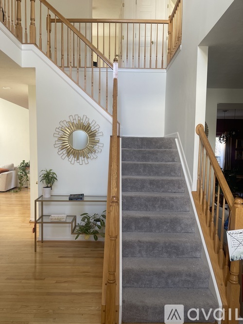 A staircase with a wooden banister and a round mirror on the wall.