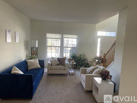 A living room with a blue couch and a white chair.