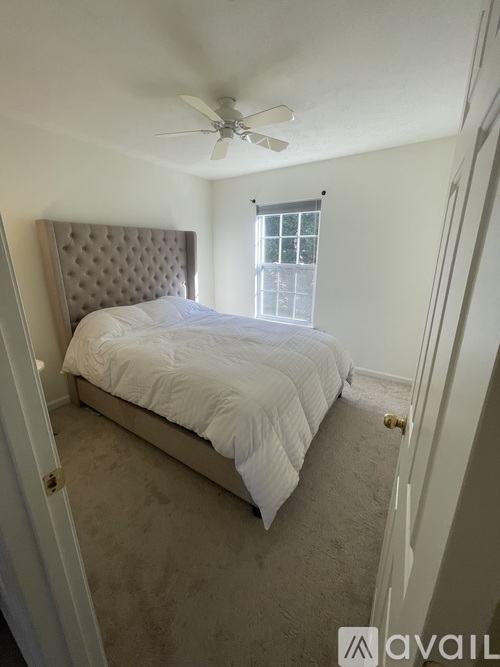 A bedroom with a bed, a window, and a ceiling fan.