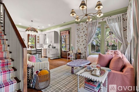 A living room with a pink couch and a chandelier.
