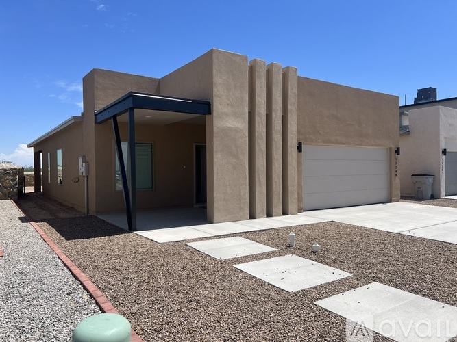 A modern house with a gravel driveway in front.