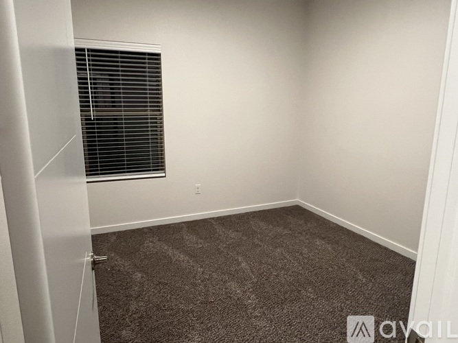 A room with a carpeted floor and a window with blinds.