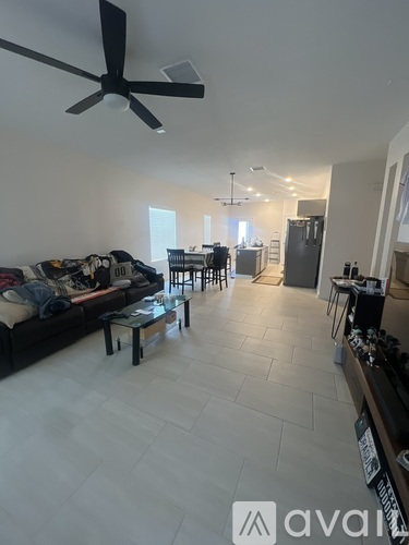 A living room with a black couch and a ceiling fan.