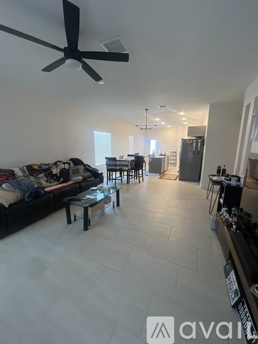 A living room with a black couch and a ceiling fan.