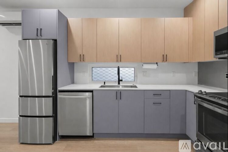A kitchen with a refrigerator, sink, and cabinets.