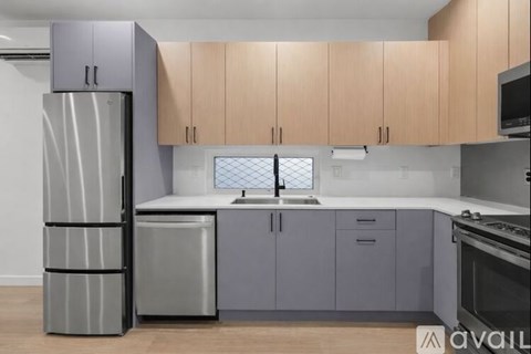 A kitchen with a refrigerator, sink, and cabinets.