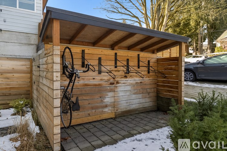 A wooden shed with a roof and a bicycle hanging on it.