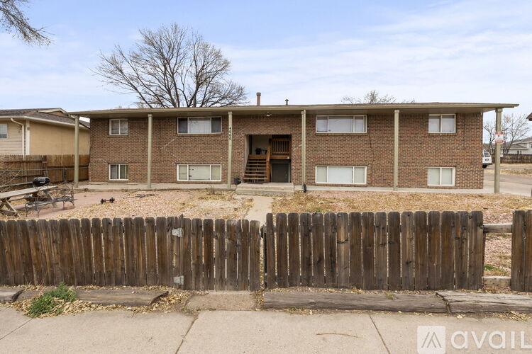 A brown brick house with a wooden fence in front.
