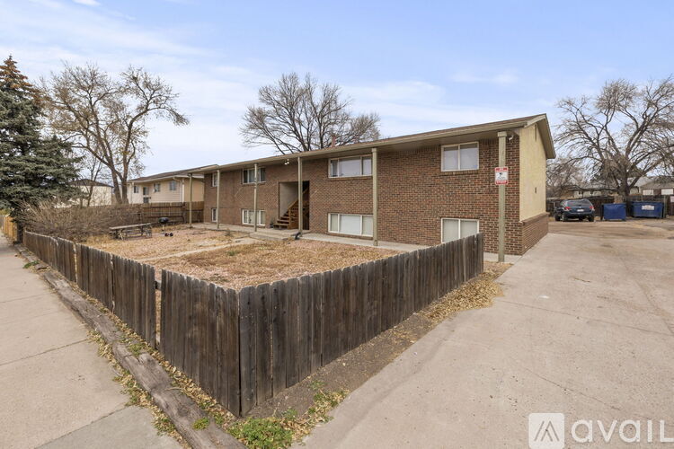 A brown brick apartment building with a wooden fence in front.