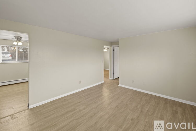 A spacious room with wooden flooring and white walls.