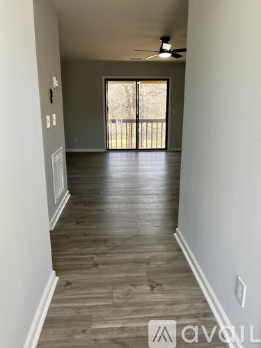 A long hallway with wood floors and a ceiling fan.