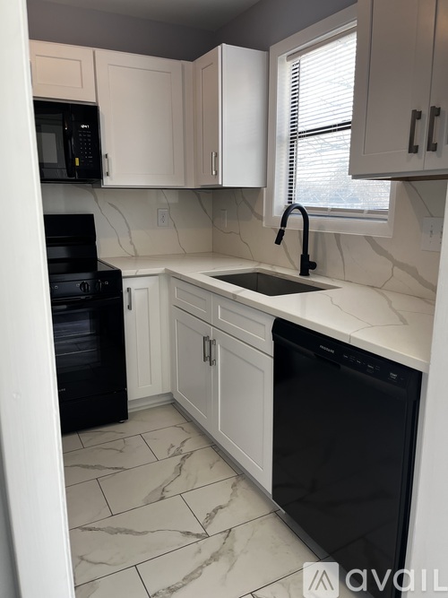 A kitchen with black appliances and white cabinets.