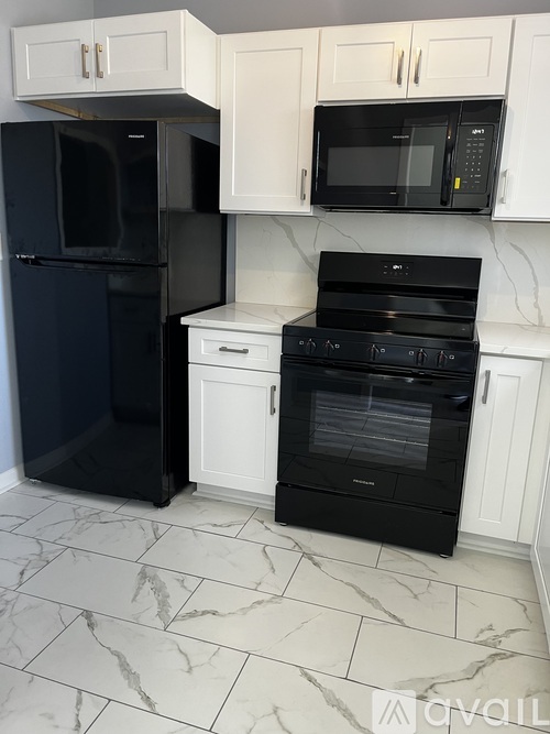 A black refrigerator and oven in a kitchen with white cabinets.