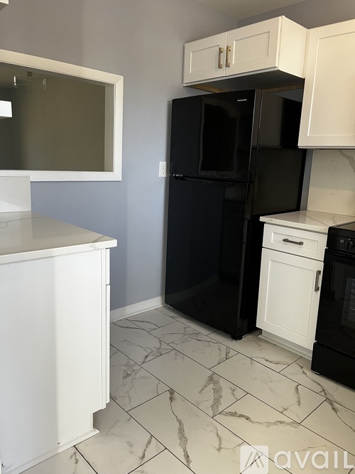 A kitchen with black and white appliances and white cabinets.