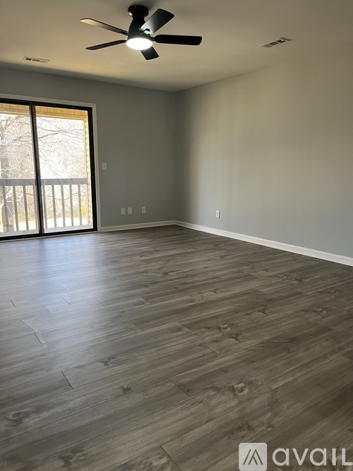 A room with a ceiling fan and wooden flooring.