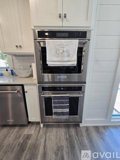 A modern kitchen with a stainless steel oven and a white towel hanging on it.