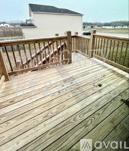 A wooden deck with a railing and a building in the background.