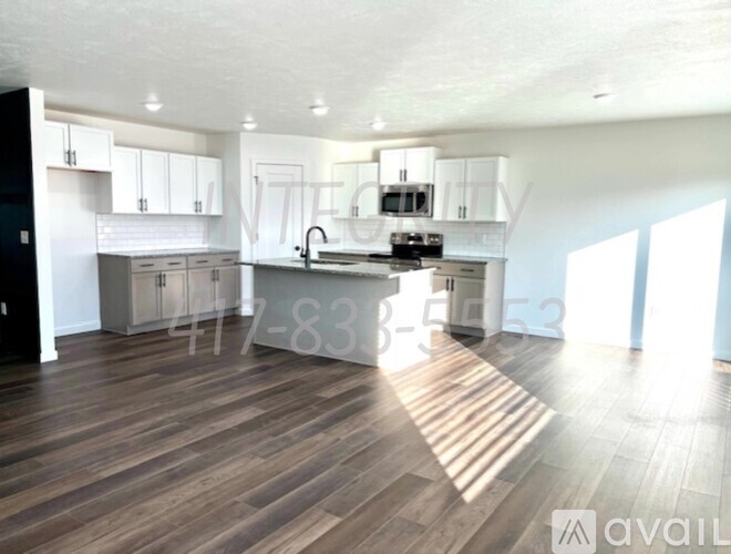 A modern kitchen with wooden floors and white cabinetry is available for rent.